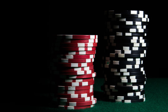 Stacks of red and black poker chips on a dark background