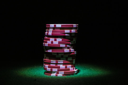 Stack Of Red Poker Chips In The Spotlight On A Dark Background