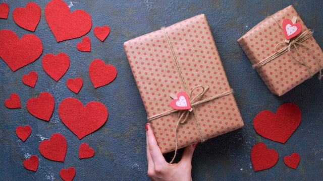 Valentine's Day holiday gift box concept of romantic love surprise appears in frame on vintage blue table with red hearts decorations flat lay. Blank space for design