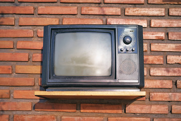 Old fashioned retro TV set on the brick wall background.
