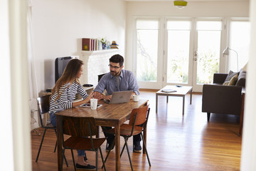 Couple Sitting At Table Using Laptop Together