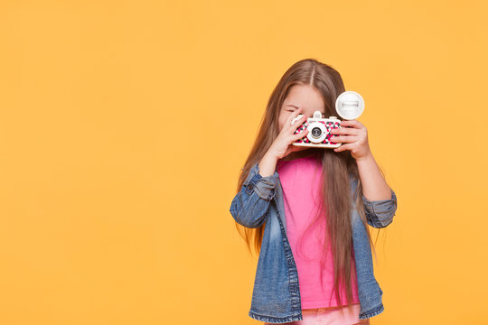 small child girl holding retro camera and taking photo