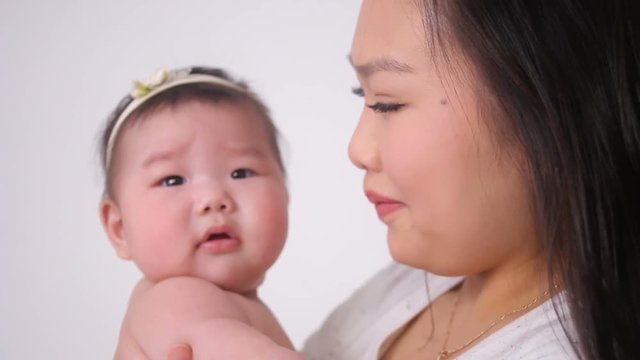 young mother kissing little daughter asian in studio