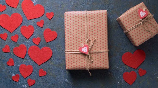Woman presents Valentine's Day holiday gift box beautiful concept of romantic love. Vintage blue table with red hearts decorations flat lay. Blank space for design