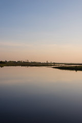 The sky in orange and blue shades is reflected on the water of the river.