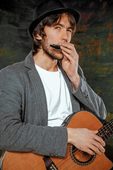 Cool guy with hat playing guitar on gray background