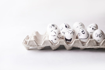 Eggs with funny faces in the package on a white background. Easter Concept Photo. Eggs. Faces on...