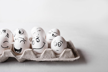 Eggs with funny faces in the package on a white background. Easter Concept Photo. Eggs. Faces on...