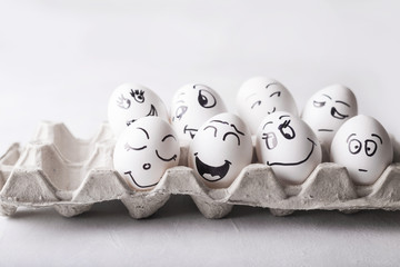 Eggs with funny faces in the package on a white background. Easter Concept Photo. Eggs. Faces on the eggs Eggs