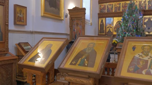 a Row of Splendid Icons in an Orthodox Cathedral and a Woman Kissing Them and Praying Not Far From a High Iconostasis in Kiev