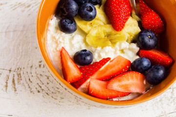 Low fat breakfast.Cottage cheese with blueberries, banana, almonds and strawberries on white background.