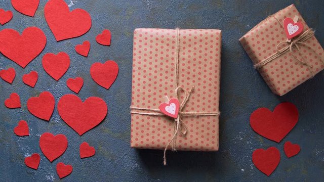 Unrecognizable men presenting Valentine's Day gift, concept of romantic love with red hearts on vintage blue table background. Top view flat lay, overhead shot