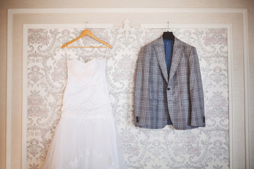 Wedding dress of the bride and the groom's suit. Hotel. Hanging.