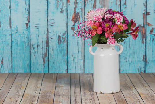 Bouquet of flowers in vintage white vase in rustic setting