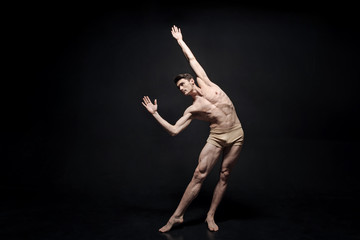 Masterful young dancer performing in the black colored studio