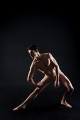 Involved young athlete stretching in the black colored studio