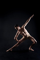 Muscular young athlete stretching in the black studio