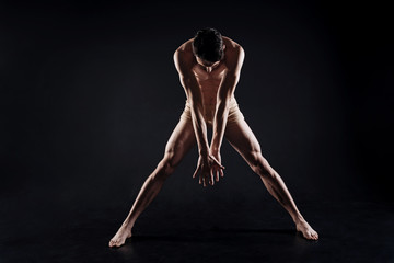 Obraz na płótnie Canvas Slim concentrated athlete stretching in the studio