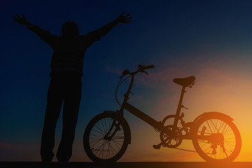 Fototapeta na wymiar Silhouette woman and bicycle on dramatic sky at sunset.