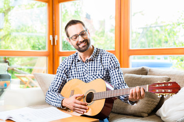 Mann spielt Gitarre daheim