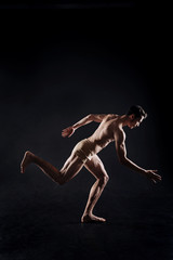 Fototapeta na wymiar Muscular athlete posing in the dark lighted studio