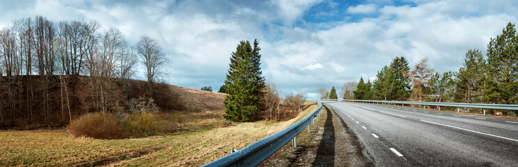black asphalt road on sunny spring day. Panoramic view in early april