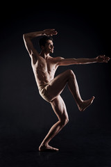 Fototapeta na wymiar Powerful young athlete posing in the dark lighted studio