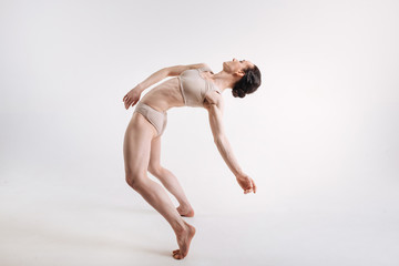 Flexible young gymnast performing against white background