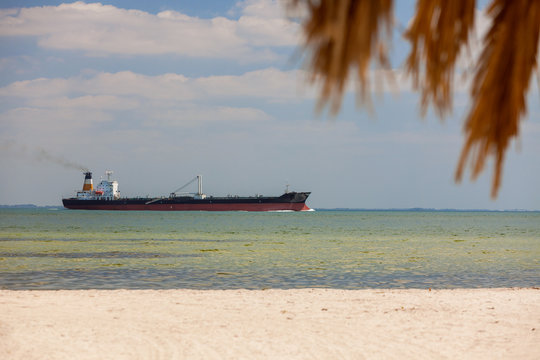 Oil Tanker Sailing Past Tropical Beach and Palm Tree