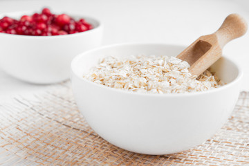 Fototapeta na wymiar Rolled oats, porridge and cranberries for a healthy breakfast in a rustic style