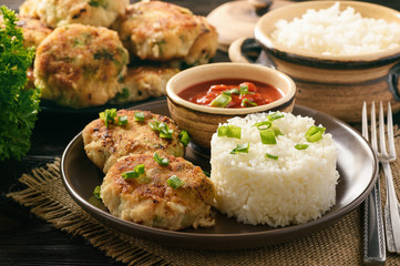 Fish cutlets with broccoli served with boiled rice.
