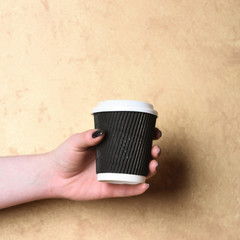 paper or plastic coffee cup in hand on textured background