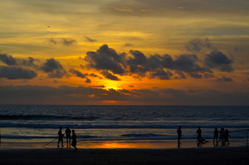 Fototapeta na wymiar Sunset beach dawn evening sky clouds orange ocean sea people silhouettes