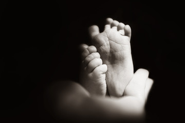 newborn baby feet on the fathers hands. black and white
