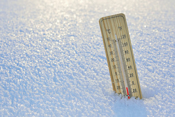 Mercury wooden thermometer stuck on snow shows very low temperatures. Temperatures in Celsius and Fahrenheit degrees. Cold winter weather. Twenty degrees under zero during the day.