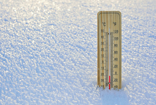 Thermometer on snow shows low temperatures - zero. Low temperatures in  degrees Celsius and fahrenheit. Cold winter weather - zero celsius thirty  two farenheit