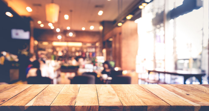 Wood table top with blur of people in coffee shop or cafe,restaurant
