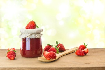 Erdbeermarmelade mit frischen Erdbeeren auf Holztisch
