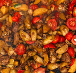 Roasted potatoes with meat and tomatoes closeup background