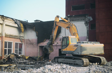 Fototapeta premium Hydraulic demolition crane dismantling school building.