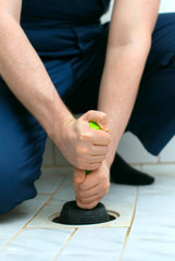Plumber repairing bathroom with hand plunger.