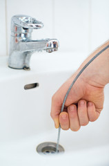 Plumber repairing sink with plumber's snake.