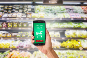 Hand holding mobile with grocery online on screen with blur supermarket background