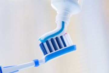 Closeup of a toothbrush and toothpaste on blurred background