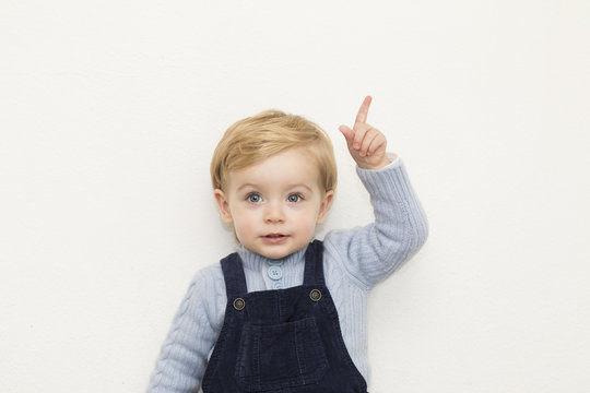 Adorable little child pointing up on white background