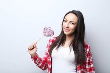 Young woman with lollipop on grey background
