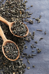 Fototapeta premium Heap of dry tea with wooden spoon on grey table