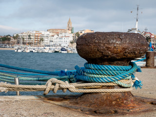 Mooring ropes, bollard on a pier, yachts and city in the backgro