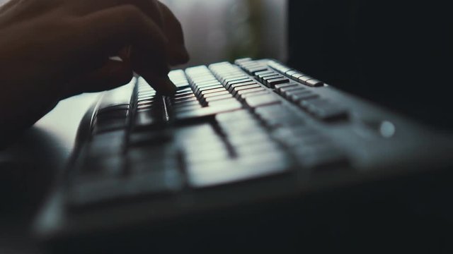Hands typing on keyboard. Window background lighting.