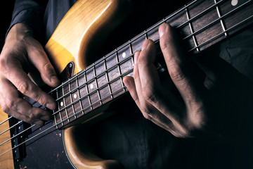 Rock music background, bass guitar player with selective focus